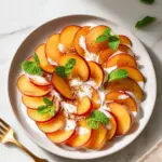Fruit Carpaccio topped with plums and lemon ginger cream, showcasing vibrant colors.
