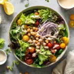 Green salad topped with lemon tahini dressing and fresh vegetables.