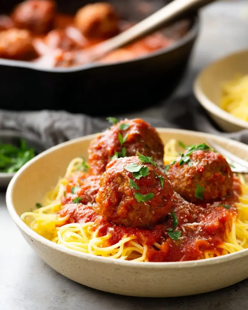 Bowl of spaghetti topped with Italian vegan meatballs and fresh herbs