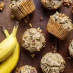 Homemade banana nut muffins with walnuts on a rustic wooden table.