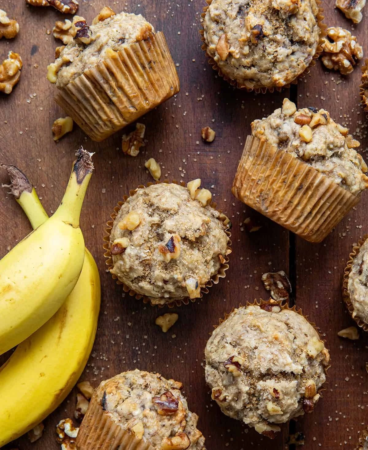 Homemade banana nut muffins with walnuts on a rustic wooden table.
