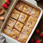 Freshly baked strawberry rhubarb cake topped with whipped cream and fresh strawberries